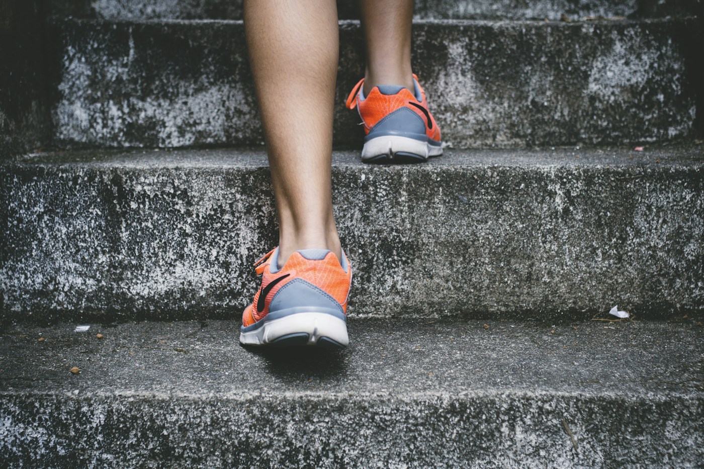 A person in trainers walking up outdoor steps